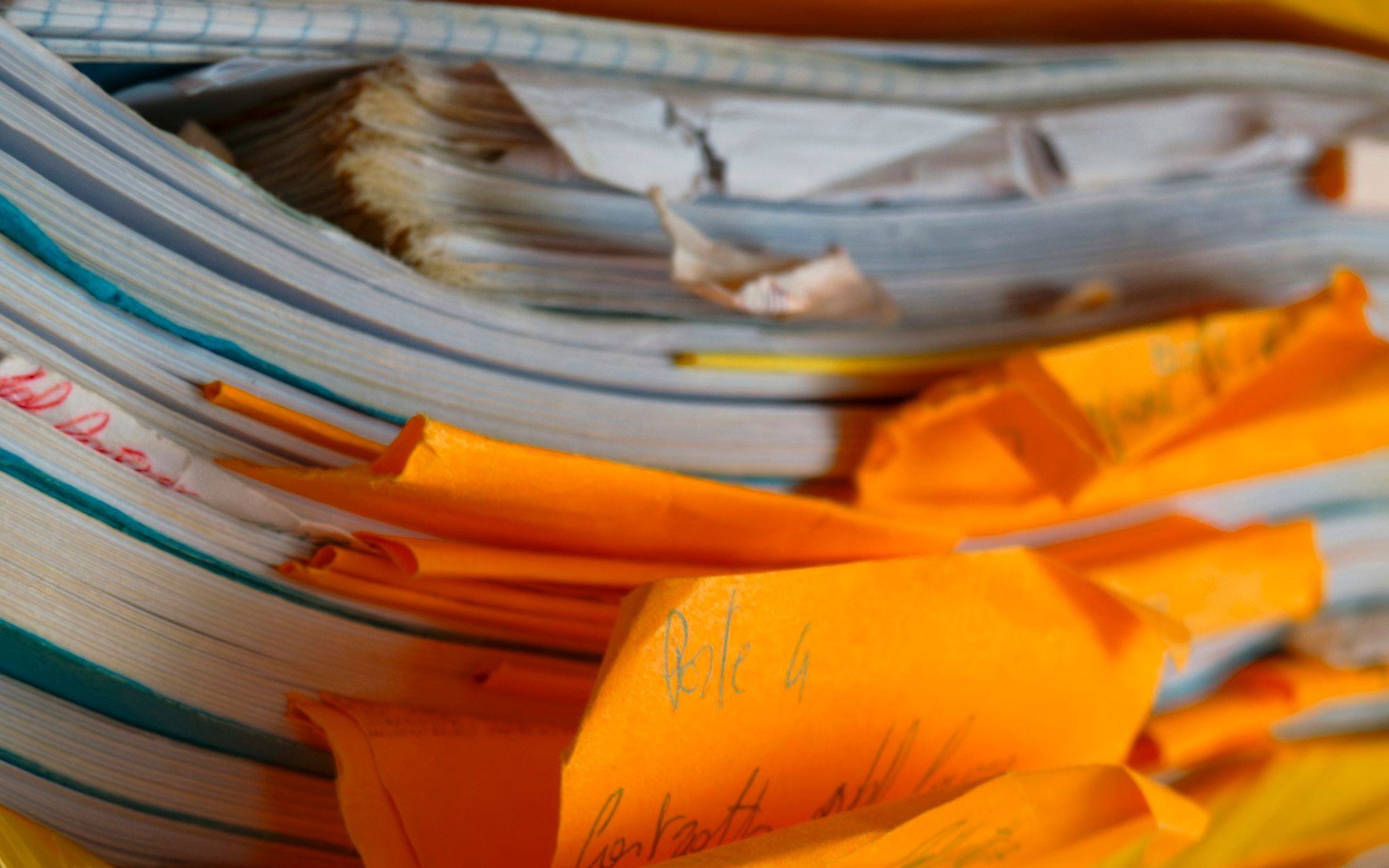 A thick, worn stack of paper files with orange dividers marked in faint handwriting.